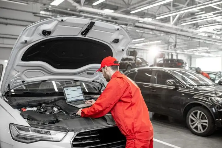 Auto mechanics doing diagnostics with laptop