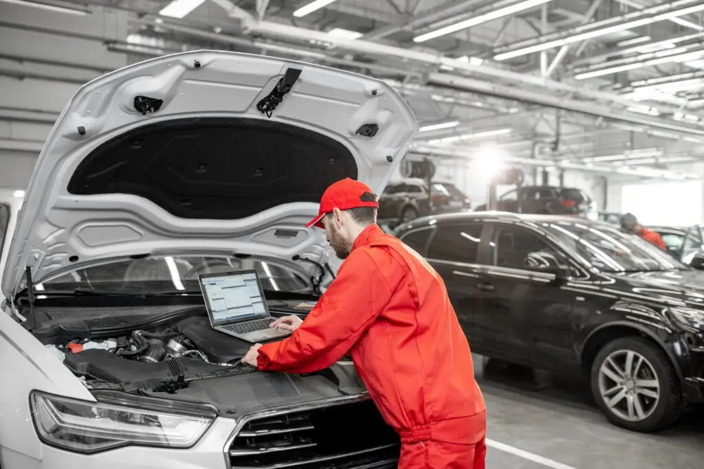 Auto mechanics doing diagnostics with laptop