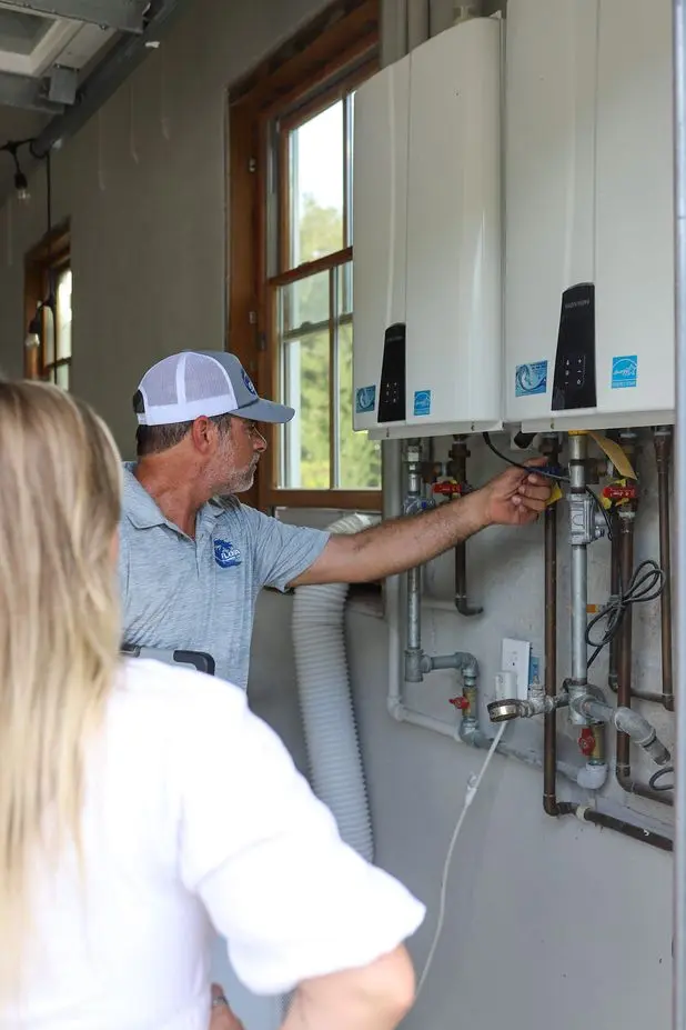 Plumber inspecting water heater installation with a client in a residential setting, showcasing plumbing expertise and hot water system maintenance.