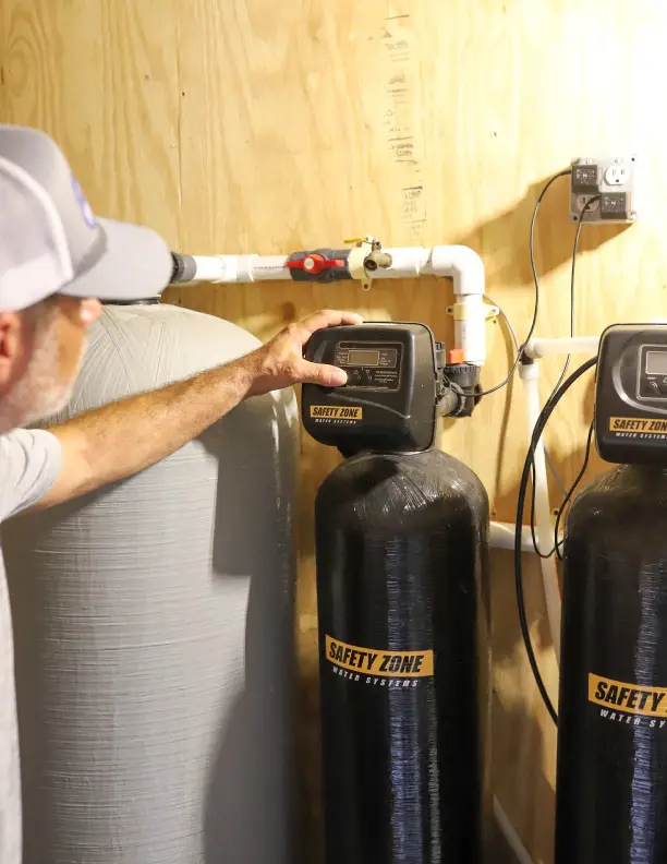 Whole house water filtration system installation, technician adjusting settings on filtration unit, ensuring safe drinking water, plumbing services in Melbourne, FL.