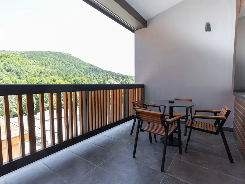 Balkon sobe u Hotel Ramonda sa stolom i stolicama i pogledom na zelene planine