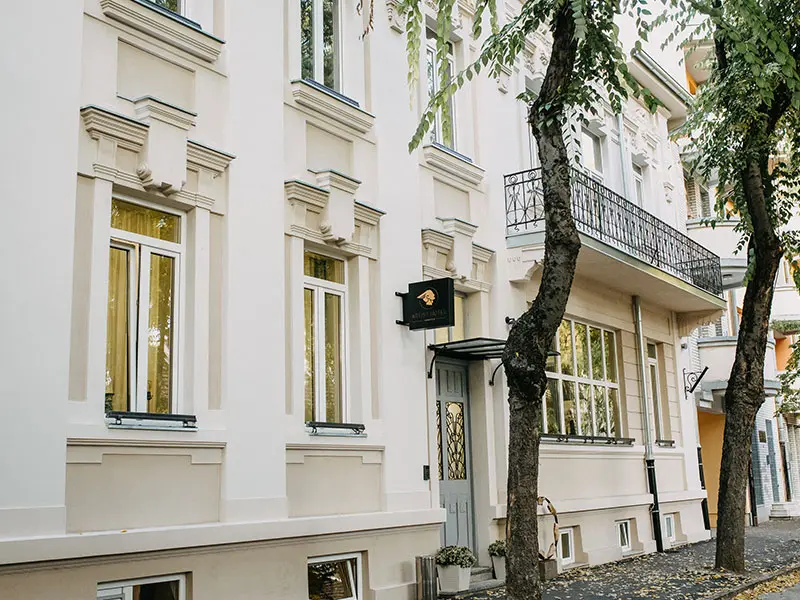 Fasada Artist Hotel Subotica sa dekorativnim okvirima oko prozora, ulaznim vratima i crnom tablom sa logoom