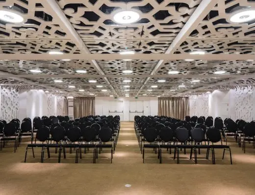 Balna sala u Zijin Hotel Belgrade sa crnim stolicama u teatarskom rasporedu, dekorativnim ornamentalnim plafonom, belim pregradama i bež zavesama