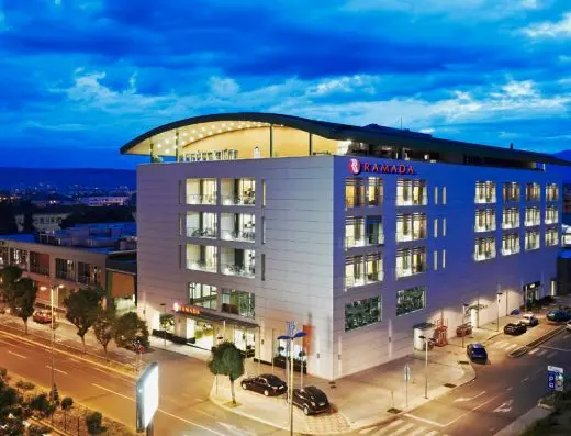 Eksterijer Hotel Ramada Podgorica noću sa osvetljenom modernom fasadom, Ramada natpisom na vrhu i panoramskim krovnim restoran