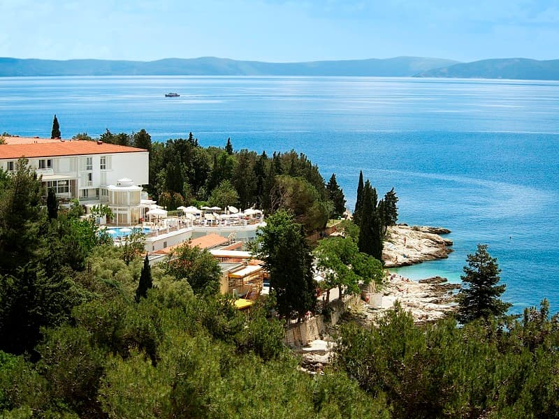 Aerial pogled na Valamar Sanfior Hotel smešten na poluostrvu sa gustim borovima, stenovitom obalom i pogledom na plavo more i planine