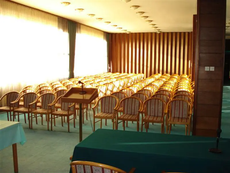 Konferencijska sala u Hotel Grand Sarajevo sa stolicama u teatarskom rasporedu, govornicom, mikrofonom i zelenim stolom na bini