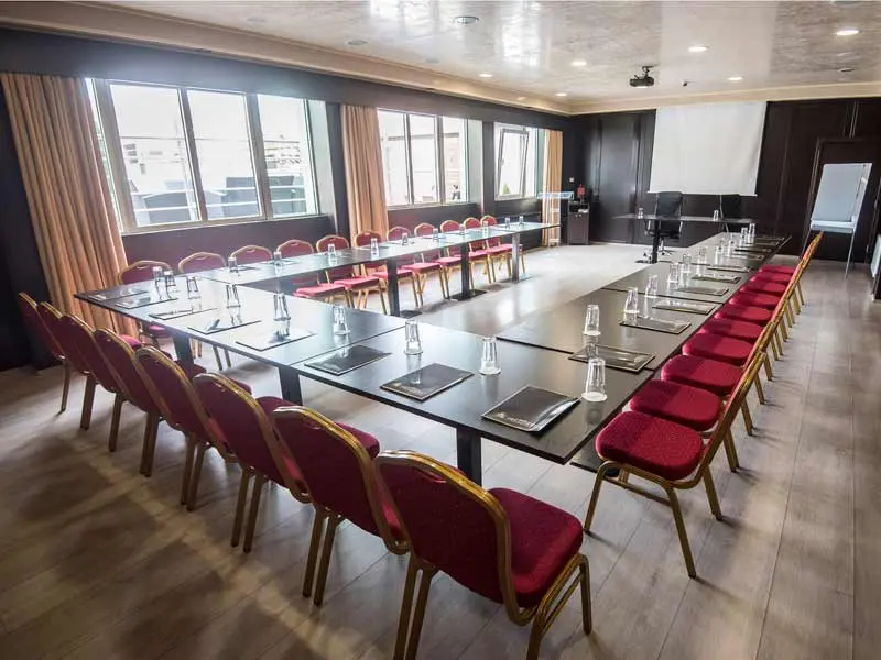 Konferencijska sala u Prezident Hotel sa U rasporedom stolova, crvenim stolicama i velikim prozorima
