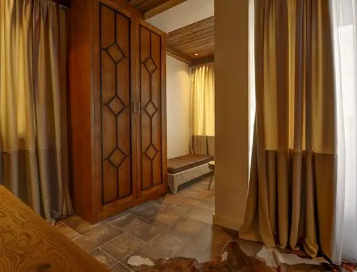 Detalj apartmana u Vila Best sa drvenim ormarom sa dijamant uzorkom, svilenim zavesama, kožnom klupom i tepihom od kravlje kože