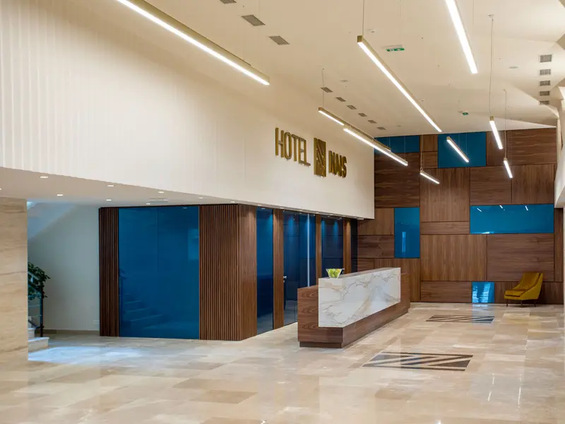 Lobi i recepcija Hotel Nais sa mermernim recepcijskim pultom, drvenim panelima sa tirkiznim staklenim akcentima, natpisom hotela i LED osvetljenjem