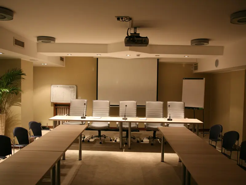 Konferencijska sala u Hotel Prestige Beograd u classroom rasporedu sa projektorom, belom tablom, flipčartom, plavim stolicama i mikrofonima na panelu