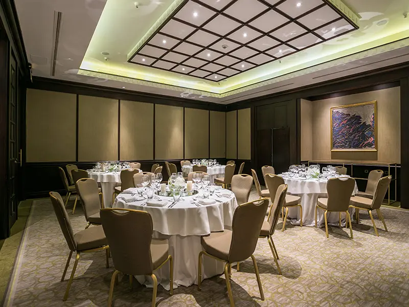 Banket sala u Hyatt Regency Beograd sa okruglim stolovima postavljenim za svečanu večeru, belim stolnjacima, cvećem i apstraktnom slikom