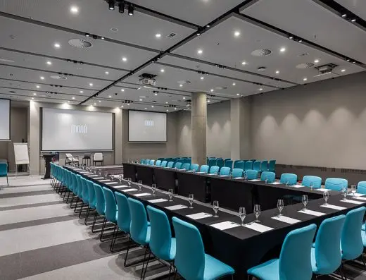 Konferencijska sala u Hotel Mona Plaza sa tirkiznim stolicama u učioničkom rasporedu i Mona Plaza logom na dva ekrana