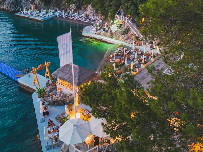 Aerial večernji pogled na Escape Plaža i Restoran sa molom, thatched krovom bara, ležaljkama na platformi i tirkiznim morem