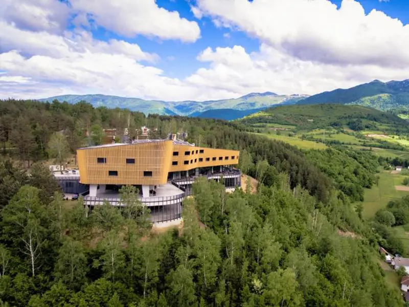 Aerial pogled na Tarčin Forest Resort & Spa Sarajevo hotel okružen gustom šumom sa zelenim planinama i dolinom u pozadini