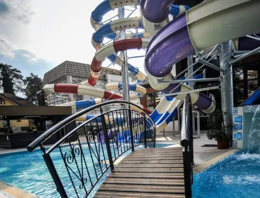 Akva park u Hotel Vrnjačke Terme sa šarenim tobogan stazama, drvenim mostom preko bazena, metalnom ogradom i pogledom na hotel
