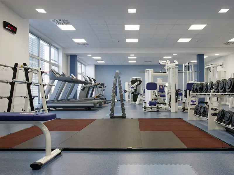 Fitnes centar u Hotel Srbija Lux sa kardio spravama, tegovima, bučicama, plavim podom i plavim zidovima