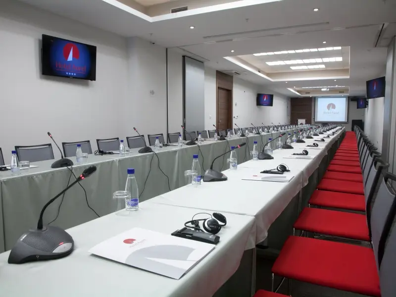 Konferencijska sala u Hotel Aurel sa dugačkim stolom, konferencijskim mikrofonima, slušalicama za simultani prevod i TV ekranima
