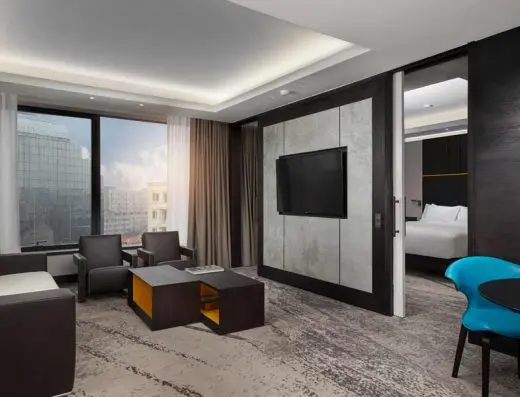 Dnevni boravak apartmana u Hilton Belgrade hotelu sa foteljama, TV-om i pogledom na grad kroz velike prozore