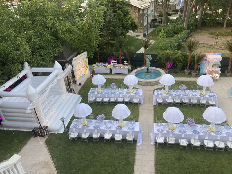Dečja proslava u bašti Muse Event House & Garden sa belim stolovima, suncobranima i naduvnim dvorcem