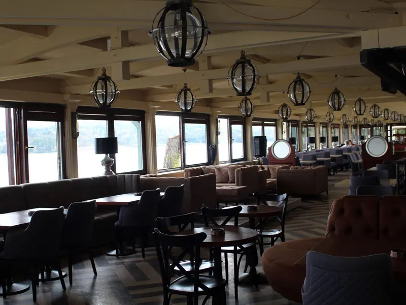 Lobi bar nautičkog stila u Turističko naselje Ribarsko ostrvo sa okruglim lampama, sofama, prozorima sa pogledom na Dunav