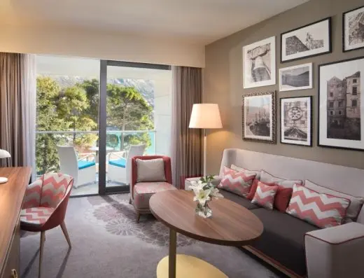 Dnevna soba apartmana u hotelu Sheraton Dubrovnik Riviera Hotel sa sivim kaučem, chevron jastucima, crno-belim fotografijama Dubrovnika i balkonom sa pogledom na more