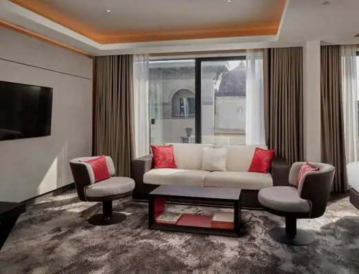 Dnevna soba apartmana u Hilton Belgrade hotelu sa kaučem, foteljama, crvenim dekorativnim jastucima i TV-om
