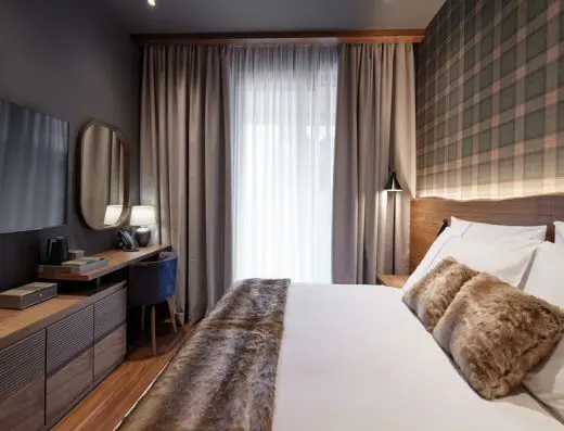 Hotelska soba u BOR Hotel by Karisma sa bračnim krevetom, krznenim prekrivačem i jastucima, kariranim tapetima i drvenim nameštajem