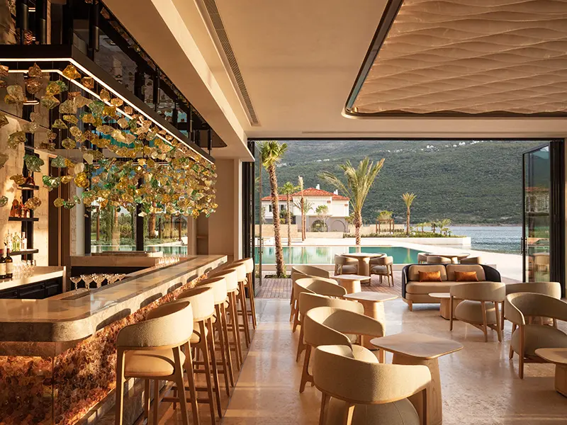 Bar u One & Only Portonovi sa staklenom umetničkom instalacijom, mramornim pultom, barskim stolicama i pogledom na bazen i more