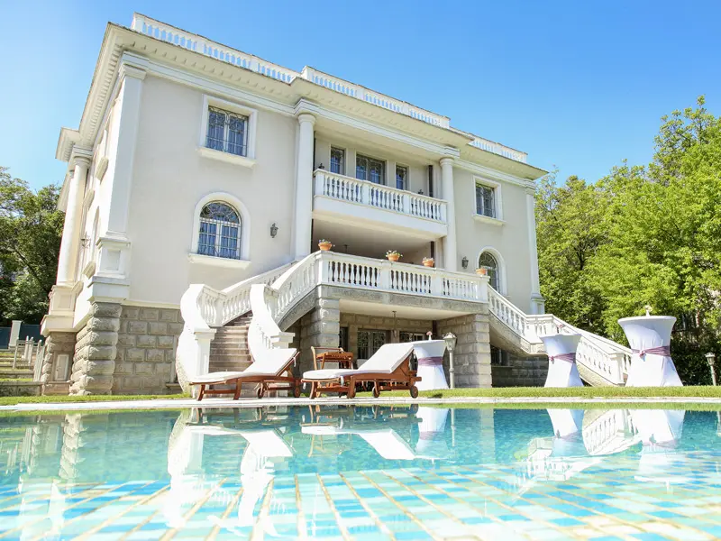 Vila Muse Event House & Garden sa belom fasadom, stepeništem, ležaljkama i bazenom u dvorištu