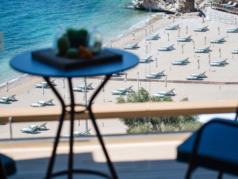 Pogled sa balkona Maestral Resort & Casino na peščanu plažu sa ležaljkama, suncobranima i tirkiznim morem