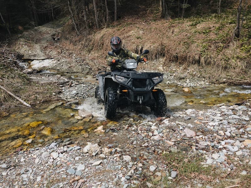 Vožnja ATV kvadom kroz potok u šumi u okolini Tarčin Forest Resort & Spa Sarajevo hotela kao deo avanturističkih aktivnosti