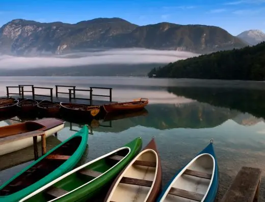 Bohinjsko jezero u blizini Bohinj Park Eco Hotel sa čamcima i kanuima na obali, drvenim molom i jutarnjom maglom iznad planina