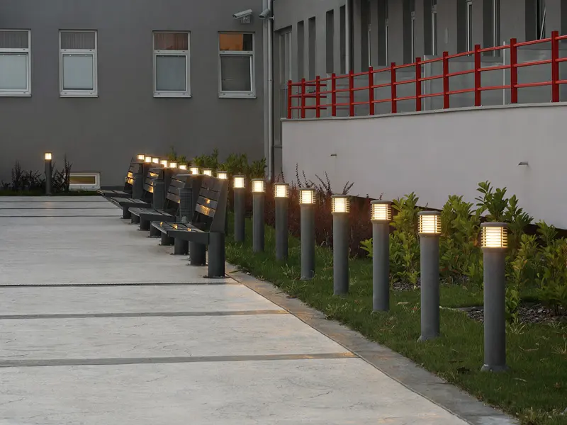 Eksterijer Hotel Srbija Lux sa šetačkom stazom, metalnim klupama, baštenskim lampama, zelenim rastinjem i crvenom ogradom u noćnom ambijentu