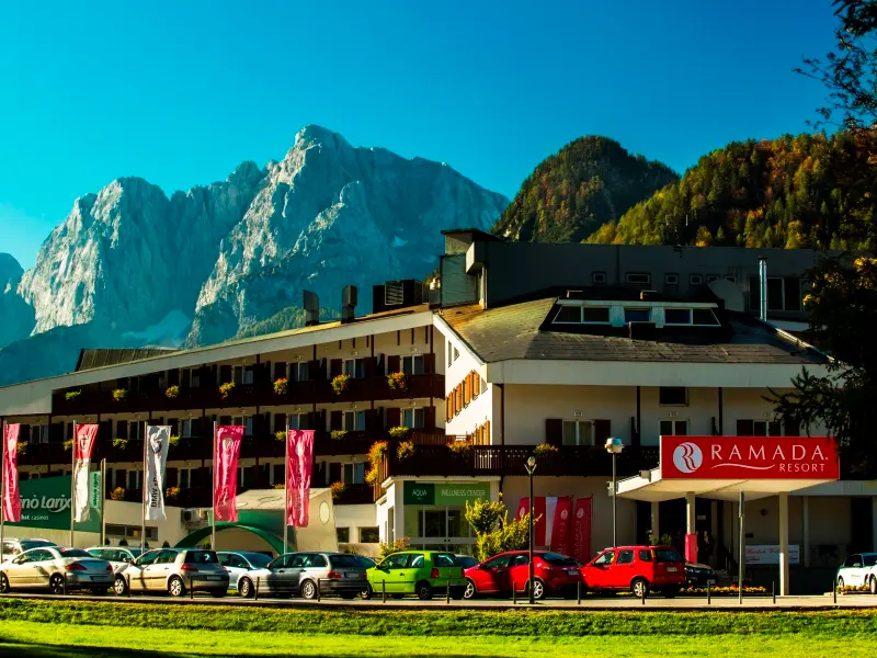 Eksterijer Ramada Resort Kranjska Gora hotela sa fasadom, parkingom i pogledom na Julijanske Alpe u pozadini