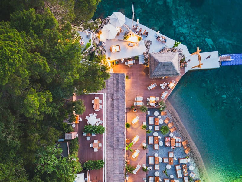 Aerial večernji pogled na Escape Plaža i Restoran sa drvenom terasom, ležaljkama na plaži, molom i kristalno čistim morem