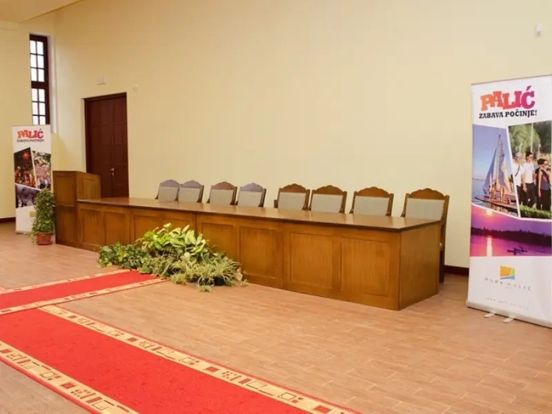 Bina sa govornicom u Kongresnom centru Velika terasa sa drvenim stolom, stolicama i reklamnim banerom