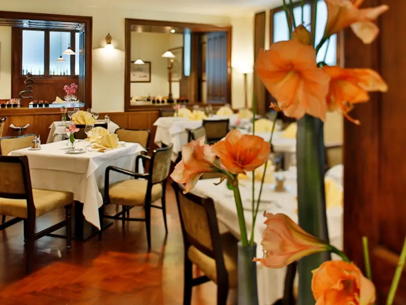Detalj enterijera Restorana Klub književnika sa narandžastim amarilis cvećem i drvenom lamperijom