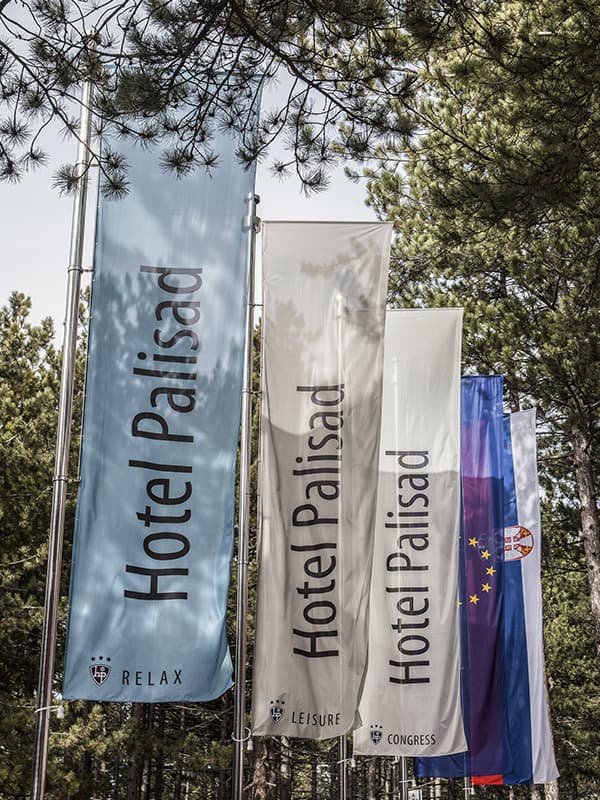 Zastave Hotel Palisad sa natpisima Relax, Leisure i Congress meÄ‘u borovim drveÄ‡em