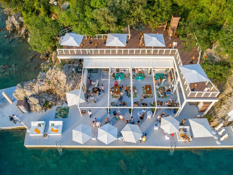 Kompleks Key West Beach & Restaurant iz vazduha sa drvenom terasom, belim suncobranima i tirkiznim morem