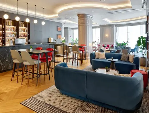 Bar u Sheraton Zagreb Hotelu sa plavim plišanim kaučima, crvenim barskim stolicama, policama sa pićima i visećim svetiljkama