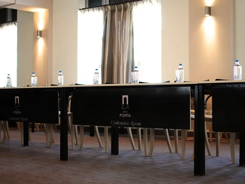 Detalj brendiranih stolova u konferencijskoj sali Hotel Porta sa natpisom Hotel Porta Conference Room i flaširanom vodom