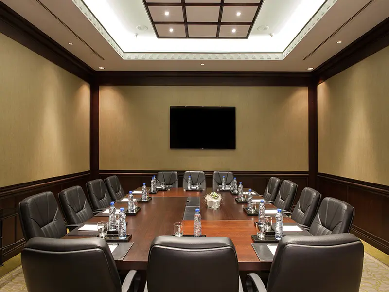 Široki pogled na klasičnu boardroom salu u Hyatt Regency Beograd sa dugim drvenim stolom, crnim kožnim stolicama i TV ekranom
