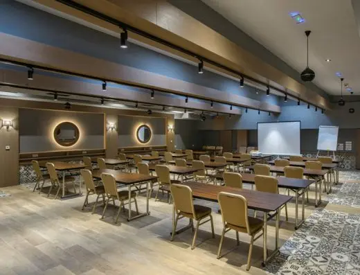 Konferencijska sala u Hotel Sunce sa učioničkim rasporedom, zlatnim stolicama, plavim zidom, projekcionim platnom i pačvork podnim pločicama