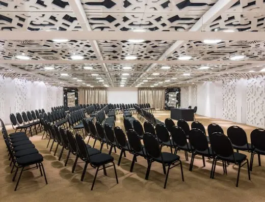 Balna sala u Zijin Hotel Belgrade sa crnim stolicama u teatarskom rasporedu, dekorativnim belim pregradama, ornamentalnim plafonom i govornicom