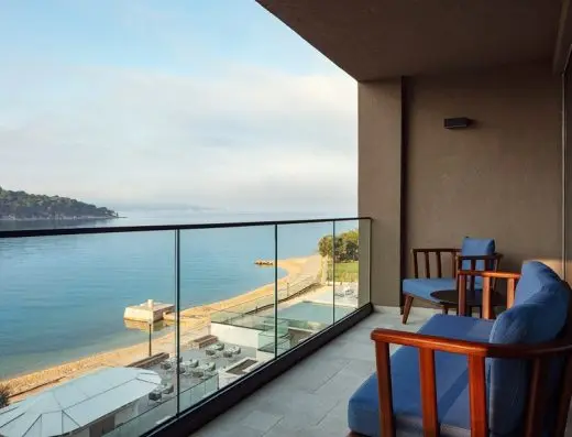 Balkon sobe u The Isolano, Cres, Autograph Collection sa drvenim stolicama, plavim jastucima i panoramskim pogledom na more i plažu