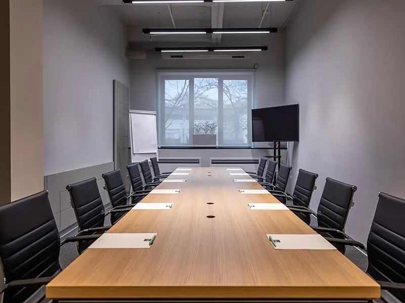 Boardroom u Hotel Mona Plaza sa dugačkim drvenim stolom, crnim kožnim executive stolicama, TV ekranom i flipčartom
