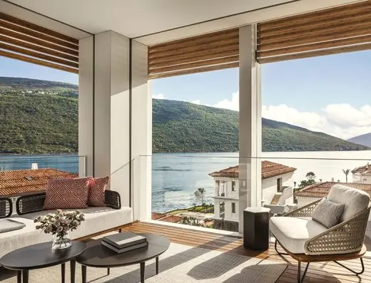 Dnevna soba apartmana u One & Only Portonovi sa modernim nameštajem, pletenom foteljom i panoramskim pogledom na more i planine
