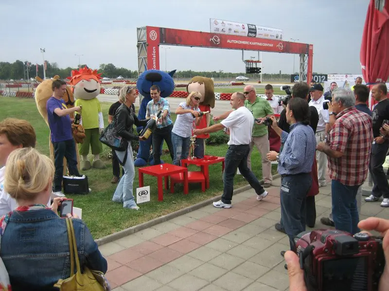 Svečana dodela nagrada na eventu u Autokomerc Karting Centar sa maskotama, trofejima, publikom i startnom kapijom u pozadini