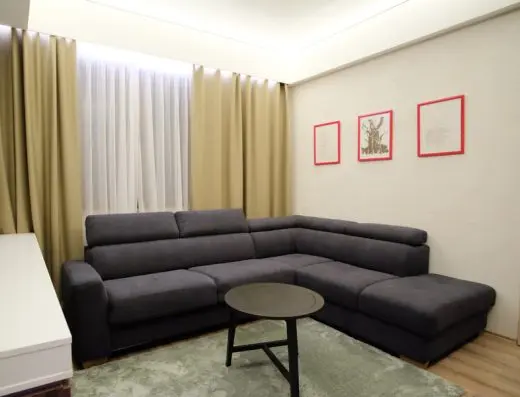 Dnevni boravak apartmana u SL Industry Hotel sa sivim ugaonim kaučem, okruglim stolićem i uramljenim slikama