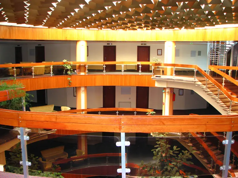 Unutrašnji atrijum u Hotel Drim sa drvenim ogradama na više spratova, geometrijskim staklenim plafonom i dekorativnim zelenilom